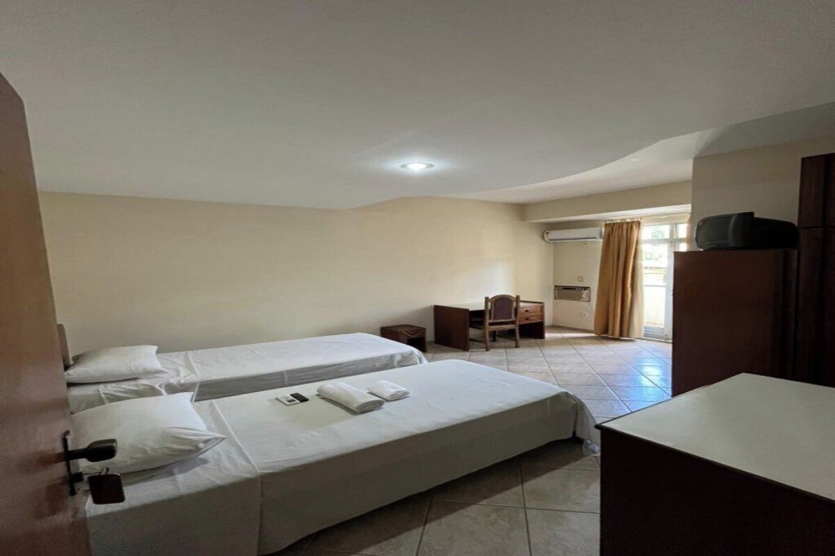 Una habitación de hotel con dos camas, un escritorio, una silla y un televisor.