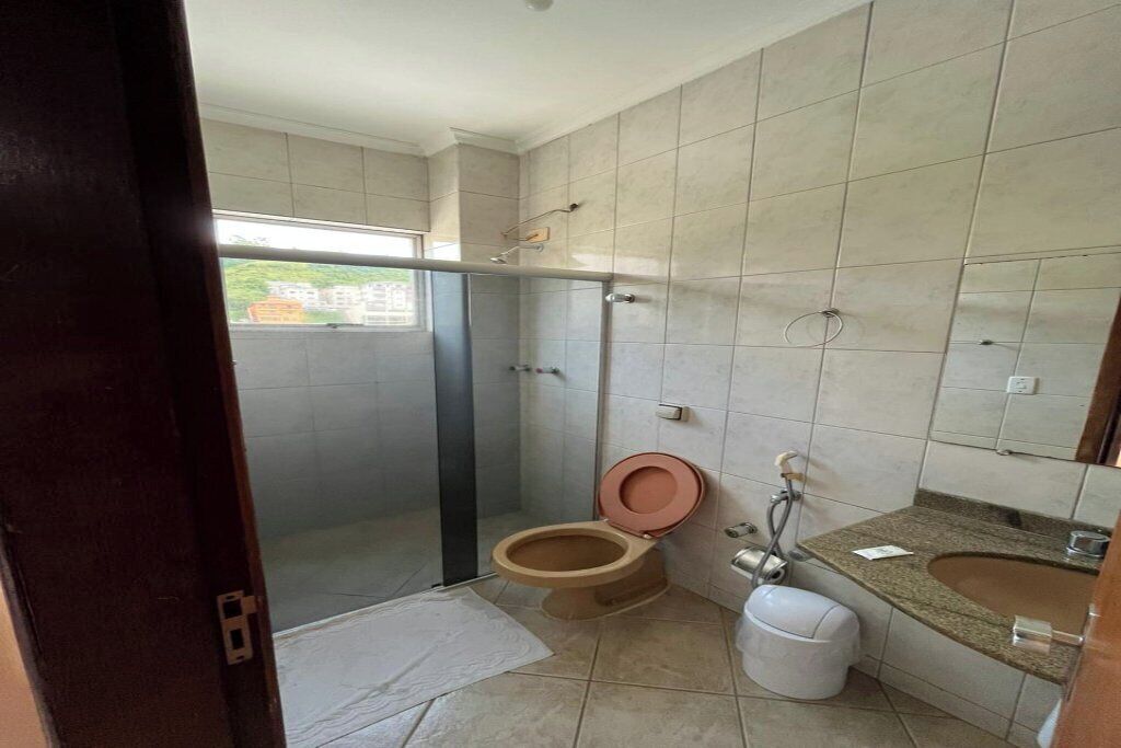 Un baño con inodoro, lavamanos, ducha y una puerta de cristal que da a un balcón.