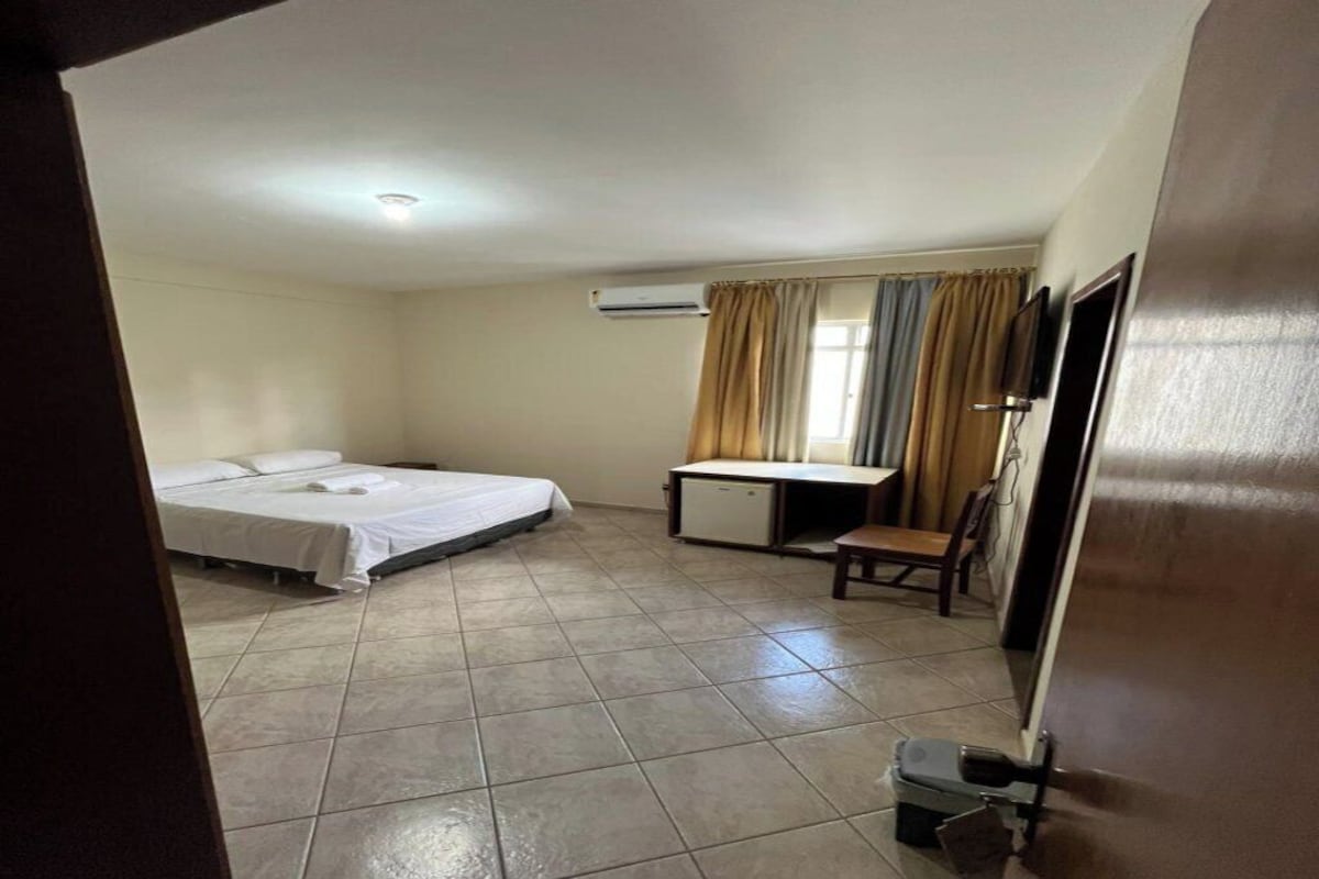 Una habitación con cama, escritorio, silla y aire acondicionado.
