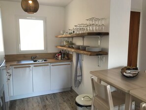 Eine Küche mit Fenster, Spüle, Holzarbeitsplatte und Regalen mit Geschirr und Gläsern.