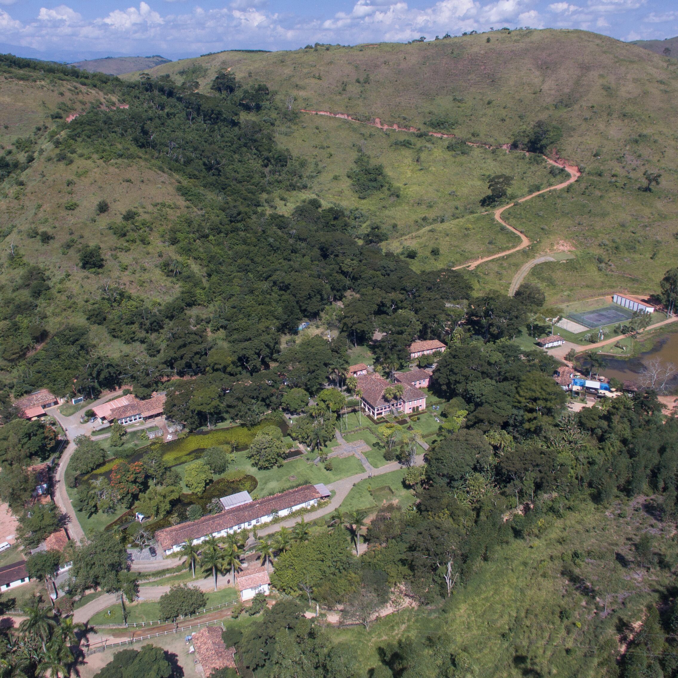 An aerial view of a residential area with houses, a winding road, and a small body of water.