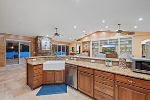 A spacious kitchen with granite countertops, wooden cabinets, a built-in oven, and a large island with a sink.