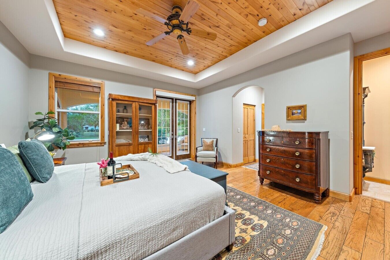 A bedroom with a bed, a dresser, a chair, a ceiling fan, and a window.