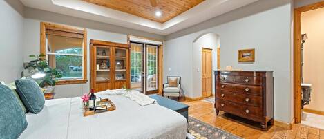 A bedroom with a bed, a dresser, a chair, a ceiling fan, and a window.
