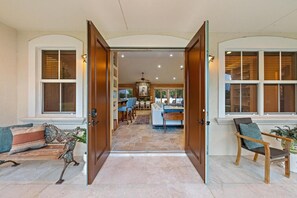 A spacious entryway leading to a living area with a dining table, chairs, and a sofa.