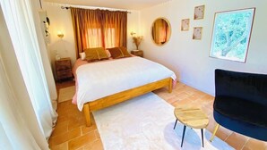 Una camera da letto con un letto, comodini, una sedia, un tappeto e decorazioni alle pareti.