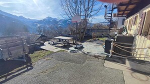 Zona all'aperto montuosa con tavolo da picnic, canestro da basket e un edificio con facciata in legno.