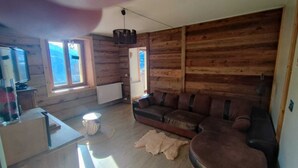 Interno di una baita in legno con un divano, un tavolino, un tamburo e un termosifone.