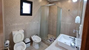 Un baño con inodoro, bidé, ducha y lavamanos.