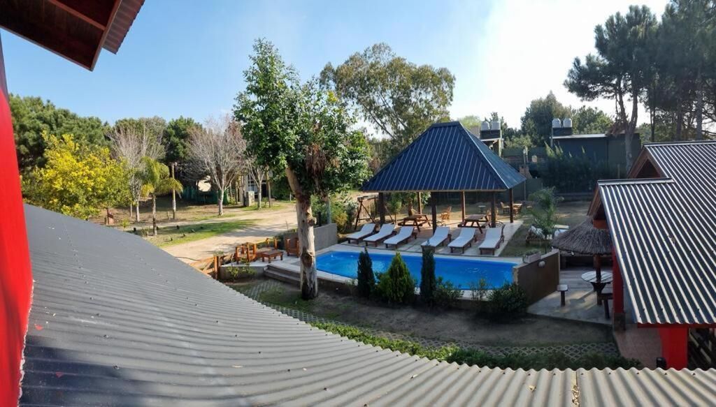 A pool area with lounge chairs, a covered seating area, and a building with a metal roof.