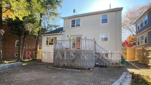 A two-story house with a paved patio, a small deck, and a brick wall. - October in Boston - Jamaica Plain Home Near Hospitals & New England Adventures (Boston)