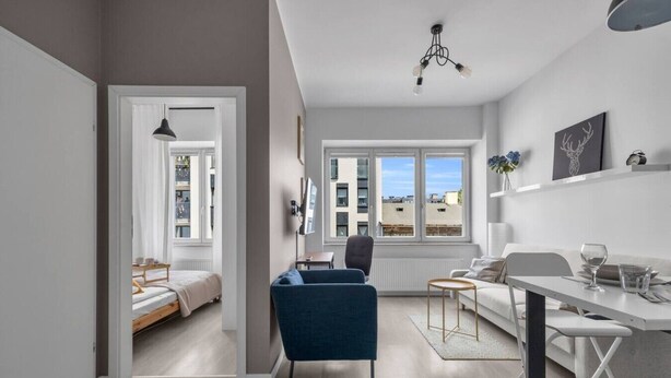 Um apartamento moderno com área de refeições, sofá, televisão e janela com vista para a cidade.