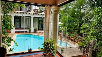 A swimming pool with a view of a building with columns and potted plants.