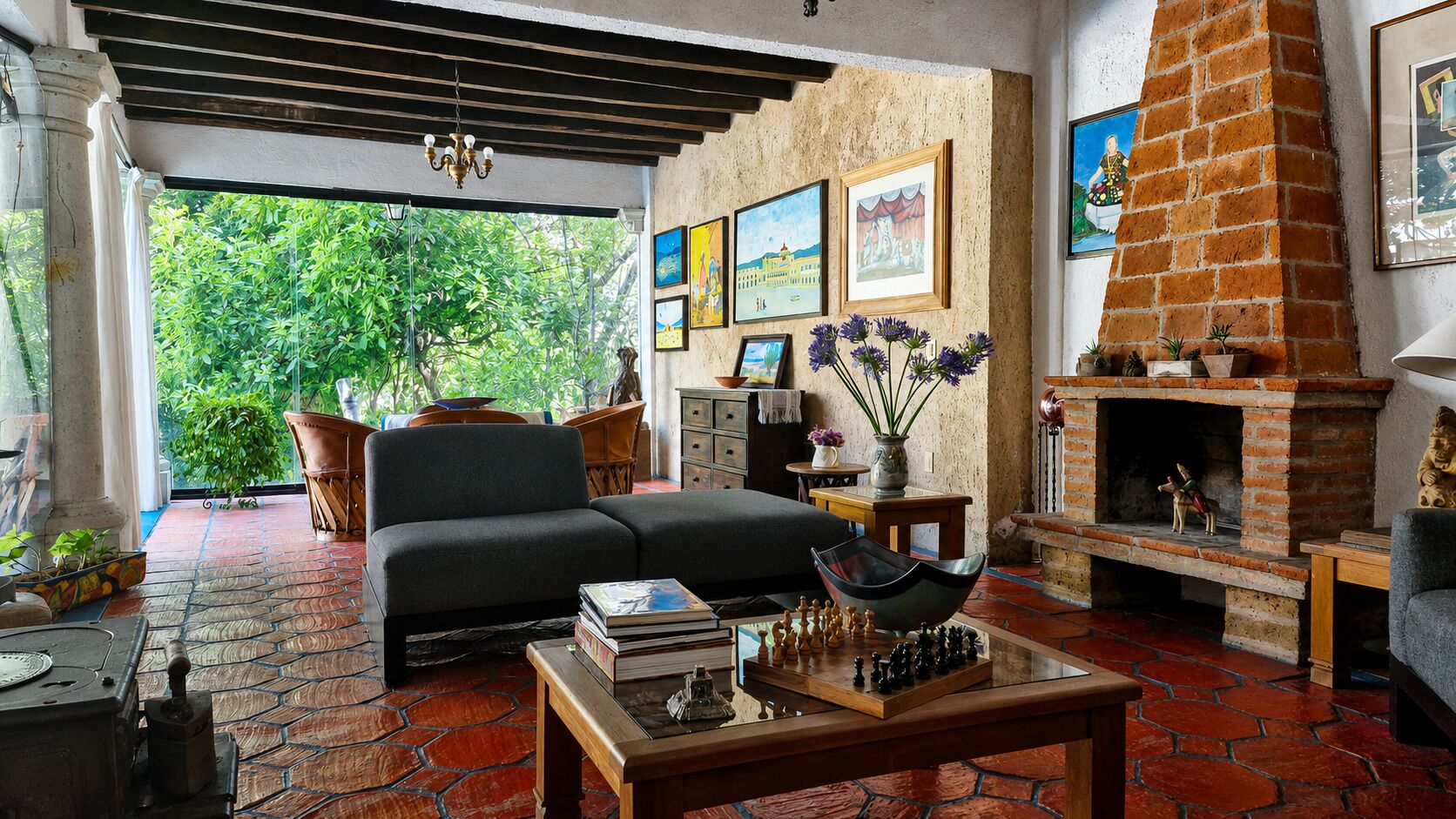 A living room with a sofa, a fireplace, and a view of greenery outside.