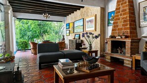 Un salon avec un canapé, une cheminée et une vue sur la verdure environnante.