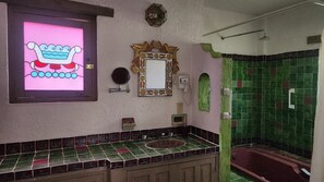 A bathroom with a tiled floor, a sink, a mirror, a shower, and a decorative frame on the wall. - Villa Oaxaca, a stately residence with 6 suites, art, culture, nature, and a pool (Oaxaca de Juárez)