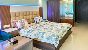 Quarto moderno com uma cama grande, mesas de cabeceira, guarda-roupa e um banheiro visível através de uma porta aberta.