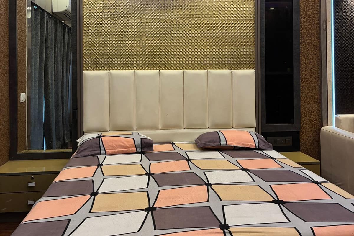 Una habitación de hotel moderna con ventilador de techo, cabecera estampada y una cama grande con edredón de diseño geométrico.