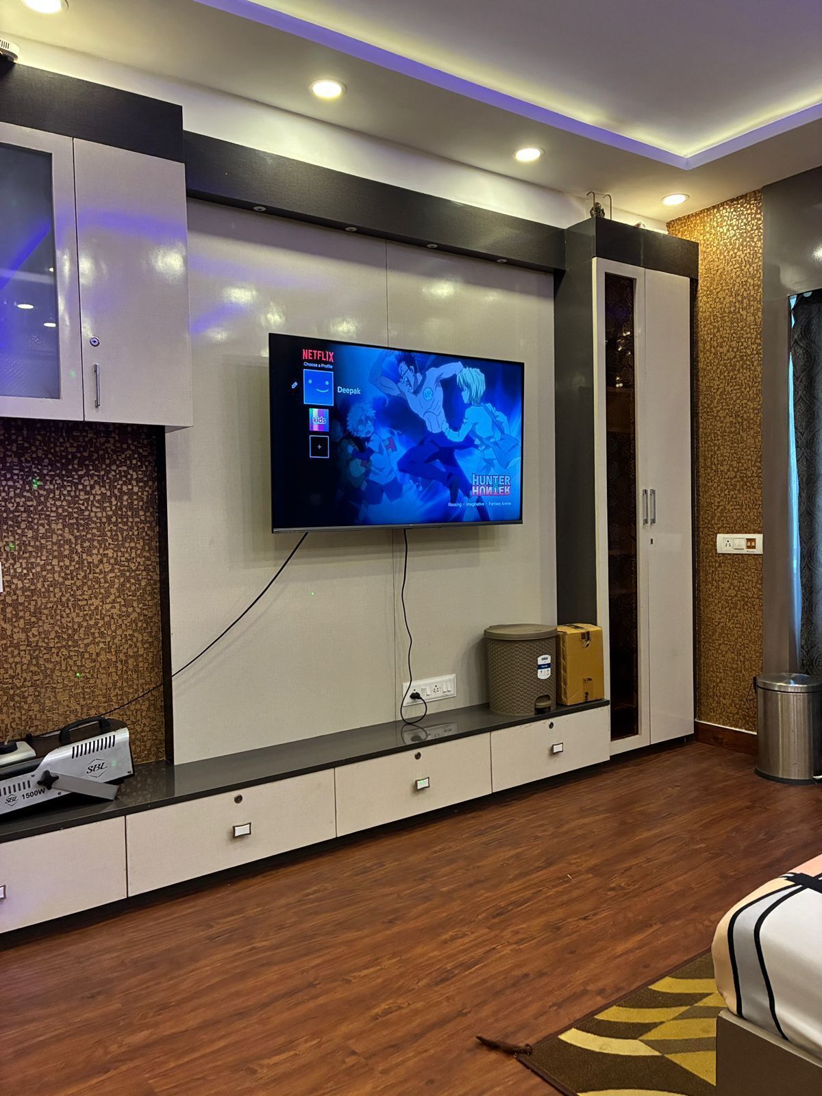 A modern living room with a flat-screen TV mounted on the wall, a built-in entertainment unit, and a wooden floor.