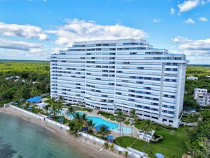 Ein Hochhaus-Hotel mit mehreren Balkonen, einem Schwimmbad und Blick auf den Strand.