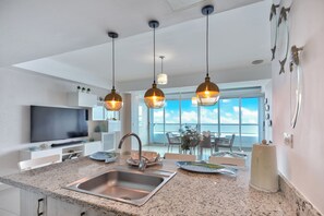 Eine moderne Küche mit Granit Arbeitsplatte, Edelstahlspüle und Pendelleuchten.