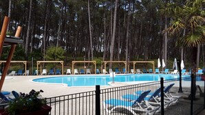 A swimming pool with lounge chairs and umbrellas, surrounded by trees. - Chalet near Mimizan in Bias in a holiday village 3KM from the ocean (Bias)