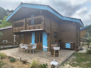 Une maison en bois à deux étages, dotée d’une terrasse, d’un espace salon extérieur et d’un coin barbecue.