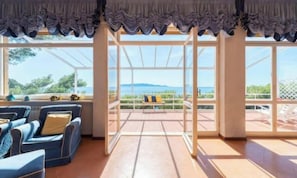 A room with a sofa, a bench, and large windows offering a view of the outdoors.