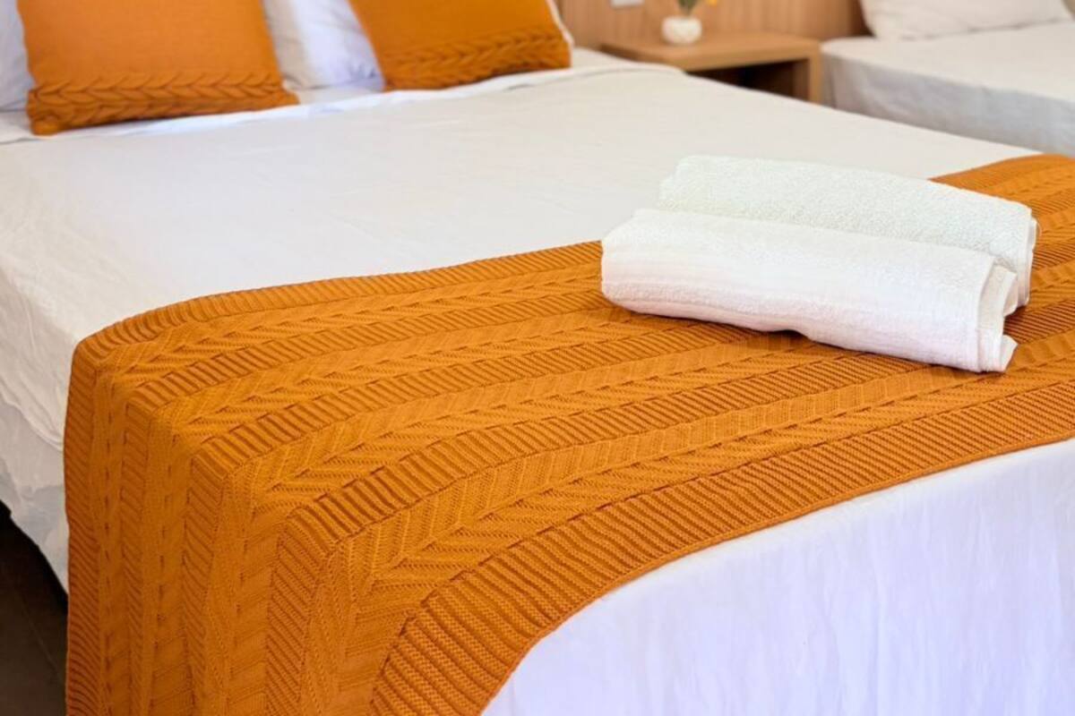 A hotel room with a bed, two pillows, a nightstand, and a folded towel.