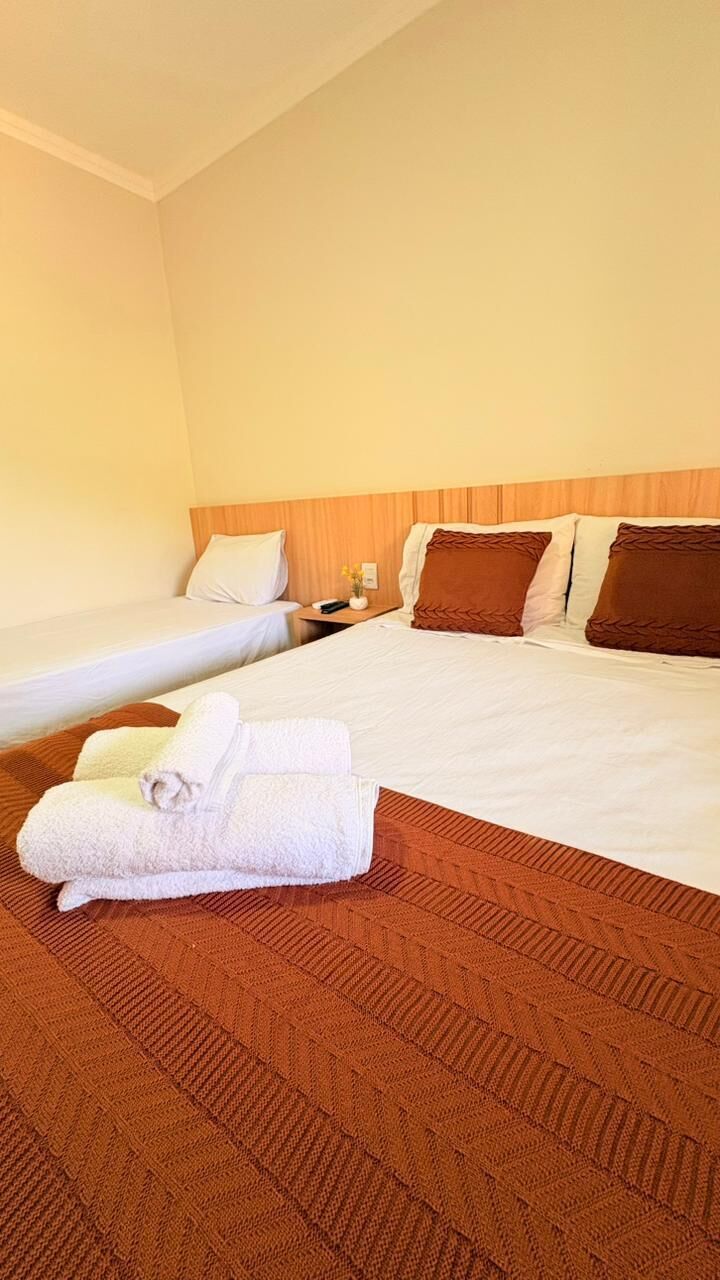 A hotel room with two beds, a wooden headboard, and a brown carpet.