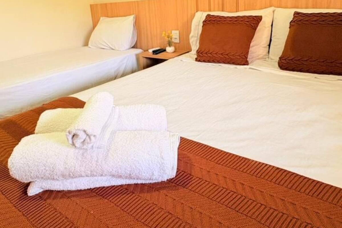 A hotel room with two beds, a wooden headboard, and a brown carpet.