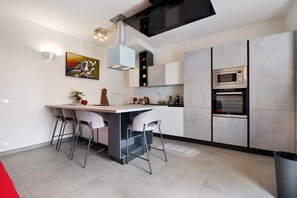 A modern kitchen with a central island, bar stools, and built-in appliances.
