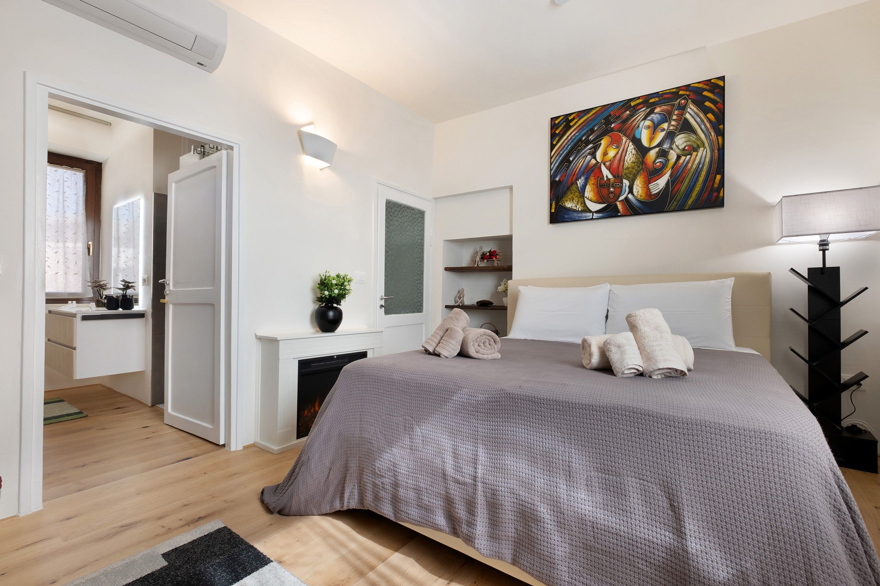 Un dormitorio moderno con una cama grande, una mesita de noche, una lámpara y un cuadro en la pared.