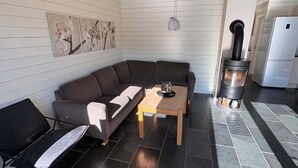 A modern living room with a sectional sofa, a coffee table, a black chair, a fireplace, and a tiled floor.