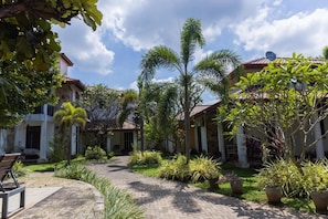 A courtyard with a paved walkway, palm trees, and potted plants. - Seahorse Villas - Three-Bedroom Apartment (NEGOMBO)