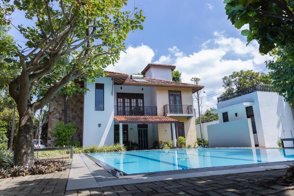 A two-story house with a swimming pool, a stone facade, and a balcony.