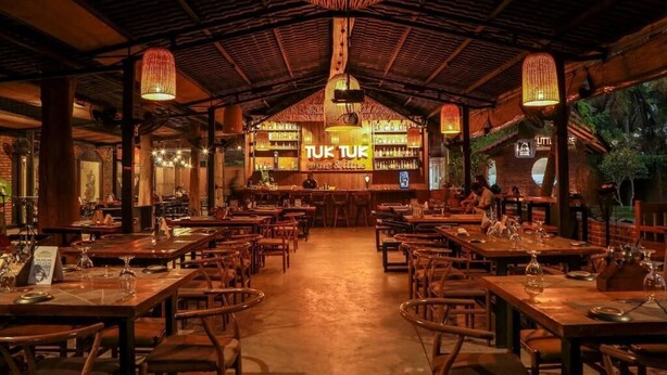 An indoor restaurant with wooden tables and chairs, a bar area, and hanging lights. - Seahorse Villas - Three-Bedroom Apartment (NEGOMBO)