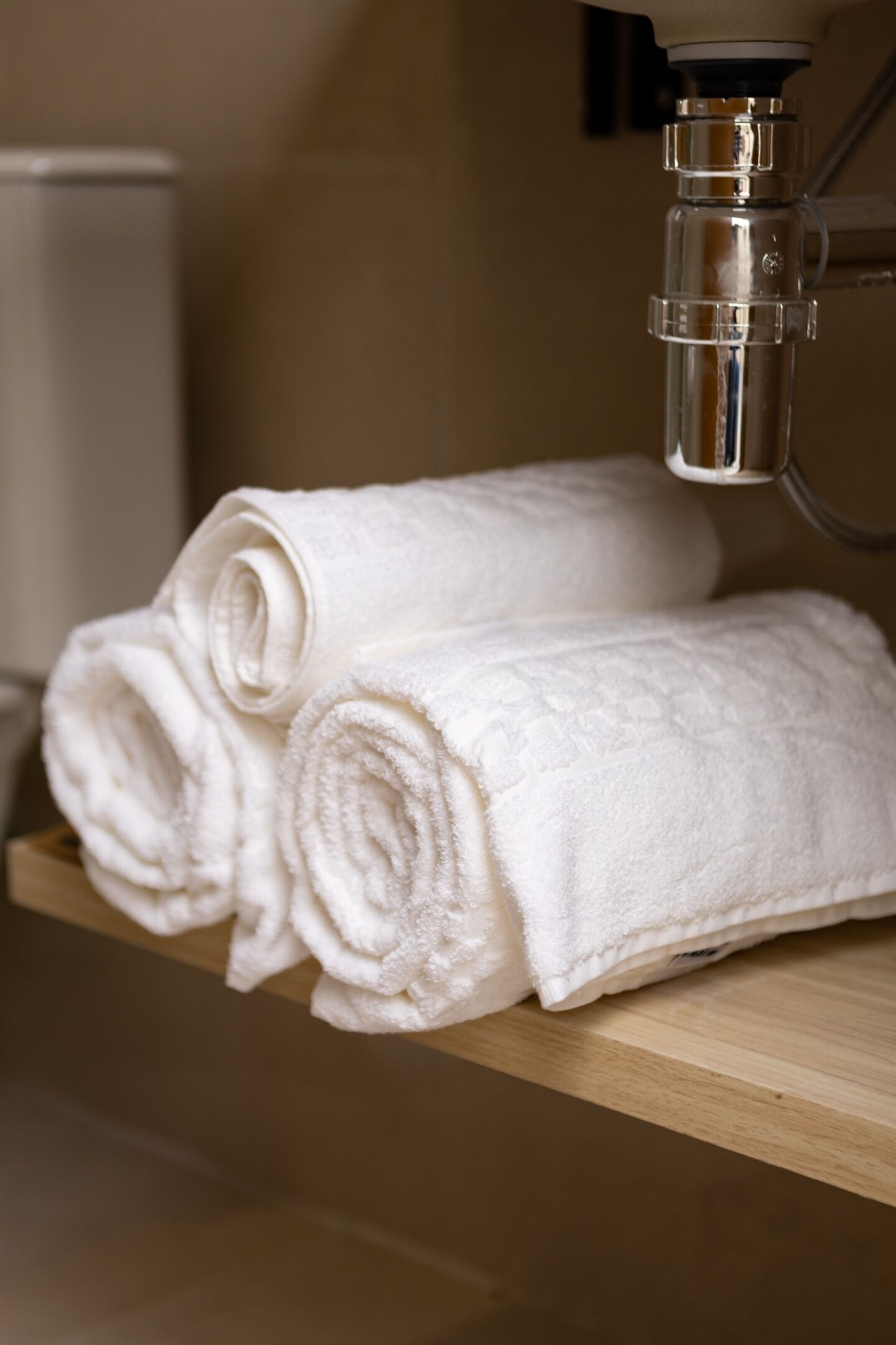 Une étagère en bois avec des serviettes blanches soigneusement pliées.