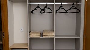 A walk-in closet with hanging space and shelves, a small appliance, and a wooden door. - Ex Hotels Laguna  (Inocência)