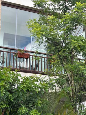 Ein Balkon mit Holzwertung, einem Blumentopf und einem Gebäude mit großen Fenstern im Hintergrund.