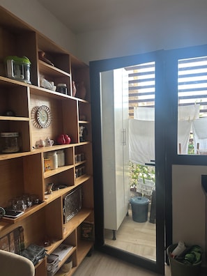 Ein Zimmer mit einer Holzeinrichtungsanlage, gefüllt mit Küchenutensilien, einer Dekorplatte und einer Tür zu einem Außenbereich mit einer Wäscheleine.