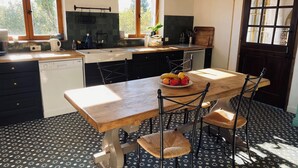 Een keuken met een houten tafel, stoelen en een fruitschaal.