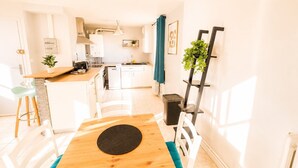A modern kitchen with white cabinets, a wooden dining table, and a black rug.