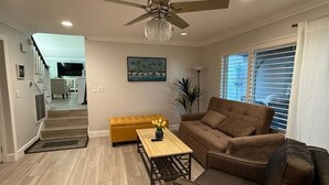 Un salon avec un canapé, une table basse, un ventilateur de plafond et un tableau accroché au mur.