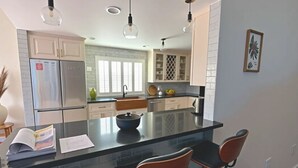 Une cuisine moderne dotée d’un îlot central, de tabourets de bar et de luminaires suspendus.