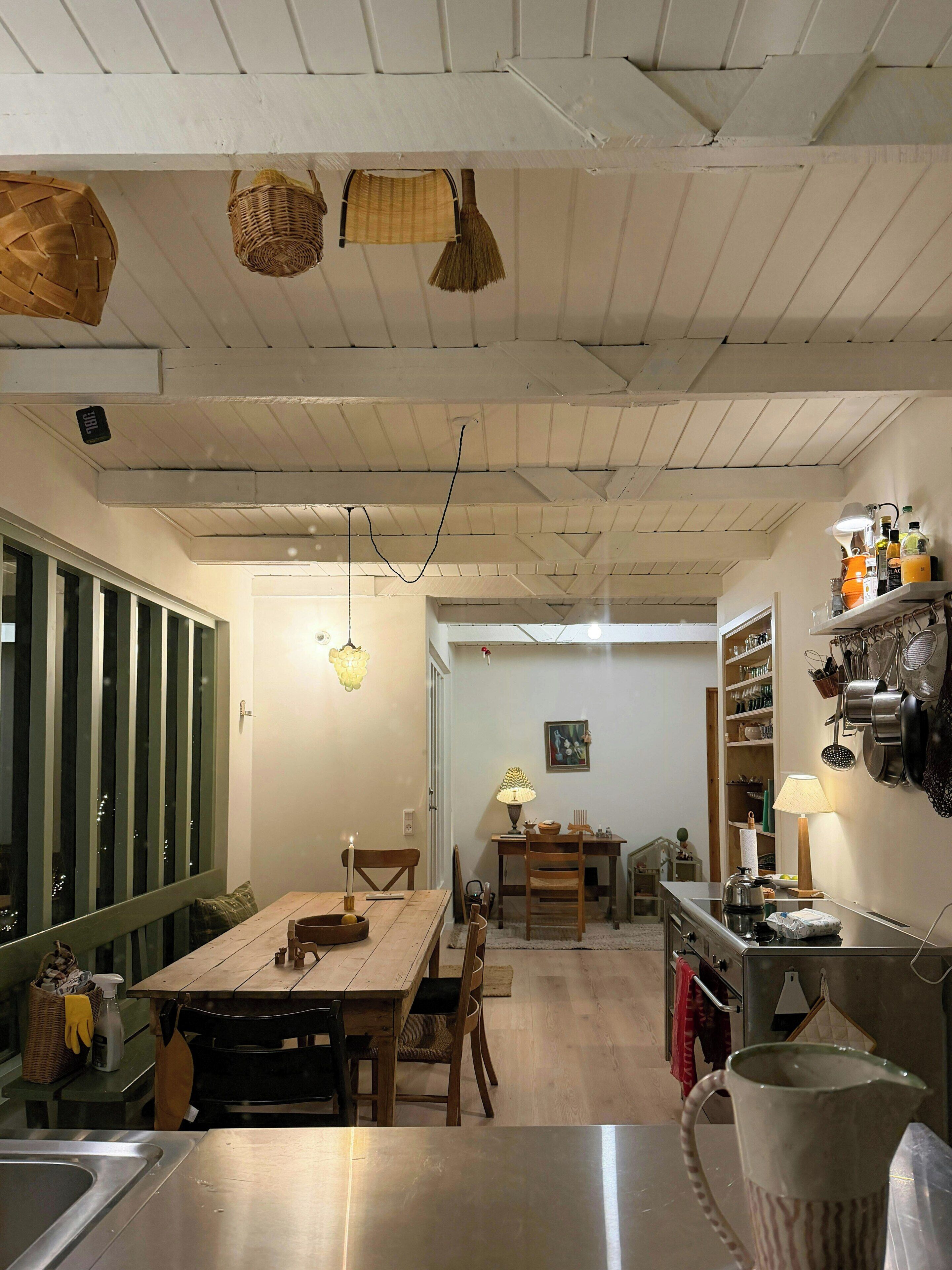 Un coin repas avec une table en bois, des chaises et des paniers suspendus.