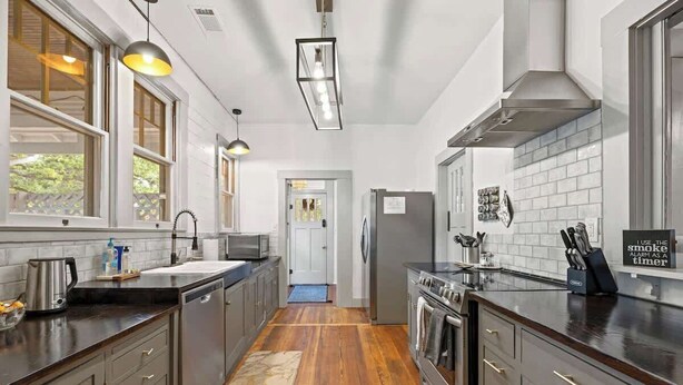 Una cucina moderna con mobili scuri, un'isola centrale, un forno integrato e un frigorifero in acciaio inossidabile.