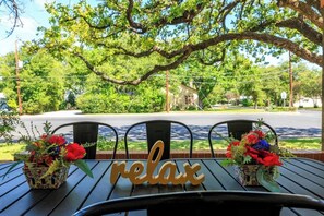 Ein Tisch mit einem 'relax'-Schild, zwei Blumenkörben und Blick auf eine Straße und Grünfläche.