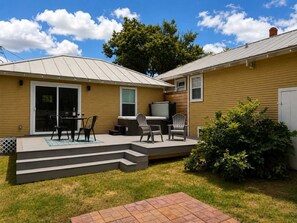 Een woonhuis met een terras, zitplaatsen buiten en een klein dek.