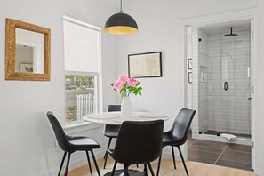 Ein modernes Badezimmer mit Duschkabine aus Glas, einem weißen Waschbecken und einer schwarzen Pendelleuchte.